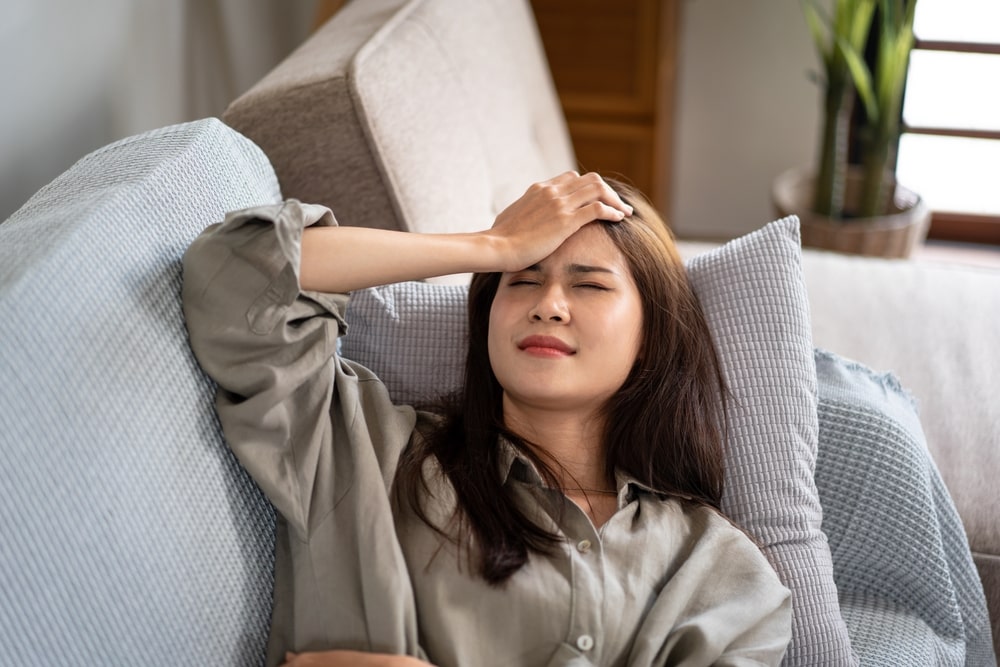 Female lying on the couch and touching forehead while feeling stressed